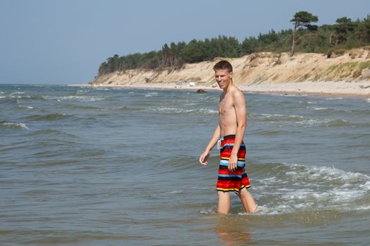 A teen boy going for a swim at a wild beach