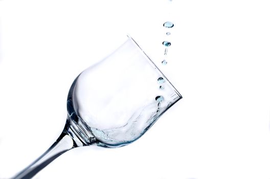 A streak of bluish fluid fills the glass glass, isolated on white