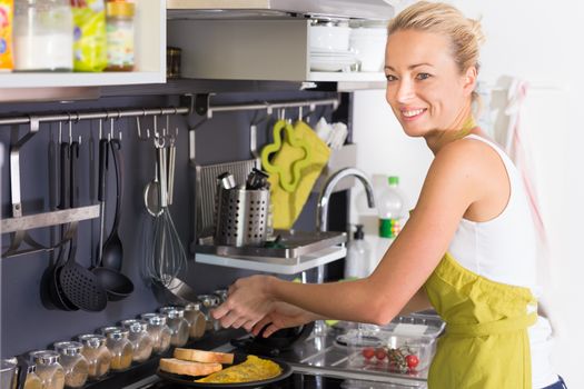 Young Woman Cooking. Healthy Mediterranean Breakfast - Home Made Egg Omlete Stuffed with Dried Tomatoes in Olive Oil and Cheese. Healthy Lifestyle. 