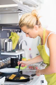 Young Woman Cooking. Healthy Mediterranean Breakfast - Home Made Egg Omlete Stuffed with Dried Tomatoes in Olive Oil and Cheese. Healthy Lifestyle. 