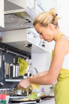 Young Woman Cooking. Healthy Mediterranean Breakfast - Home Made Egg Omlete Stuffed with Dried Tomatoes in Olive Oil and Cheese. Healthy Lifestyle. 