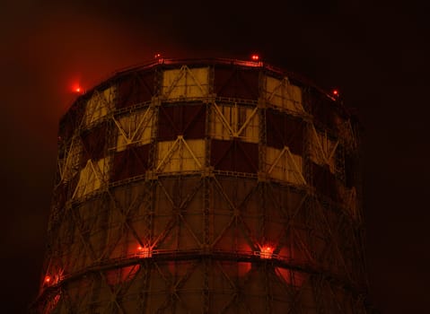 Pipe energy sector emits smoke into the atmosphere. Night view. Lights red lanterns