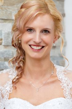 home portrait of beautiful blonde smiling bride dressed to white clothe