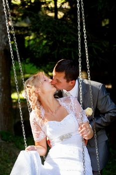 beautiful young wedding couple, blonde bride kissing her groom outdoor