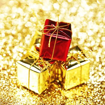 Decorative red and gold boxes with holiday gifts on shiny glitter background