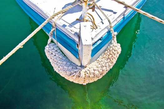 Old wooden fishing boat prow in green sea water