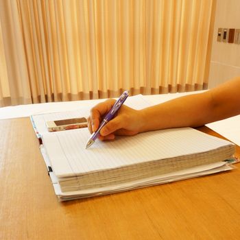 Woman sitting on chair currently writing a memory note on the table.                              