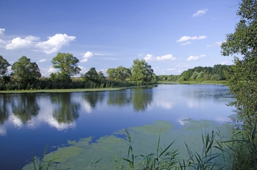 Summer landscape with low clouds. reflected on the surface of the broad river in a Sunny day