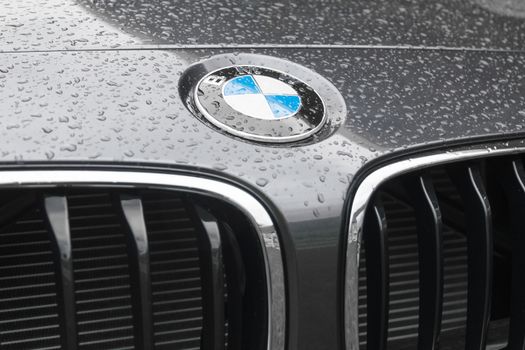 MUNICH, GERMANY - AUGUST 9, 2014: BMW logo on wet surface of hood of new model elite deluxe car. BMW is part of the "German Big 3" luxury automakers, which are the three best-selling luxury automakers in the world.