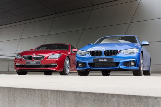 MUNICH, GERMANY - AUGUST 9, 2014: New modern models of executive business class BMW cars. Red 640i and blue 425d wet after rain autos.