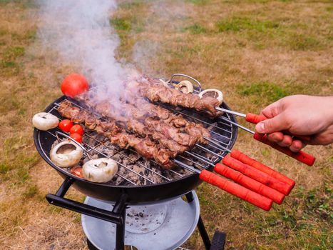 Closeup of a chef turning skewers of meat on hot barbecue