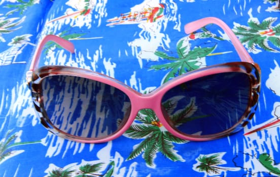 Womans sunglasses laying on the beach summertime
