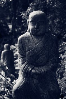 Ruined stone statue Ksitigarbha Bodhisattva in garden.
