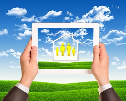 Hands holding tablet computer with the image of house and family icons. Nature landscape as backdrop