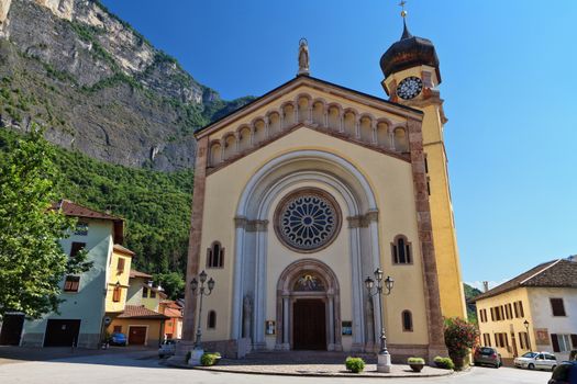 church in Mezzacorona village on sunny summer day with mountains in the background, Trentino, Italy