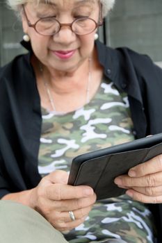 Senior women relaxing at home reading E-book on her tablet.