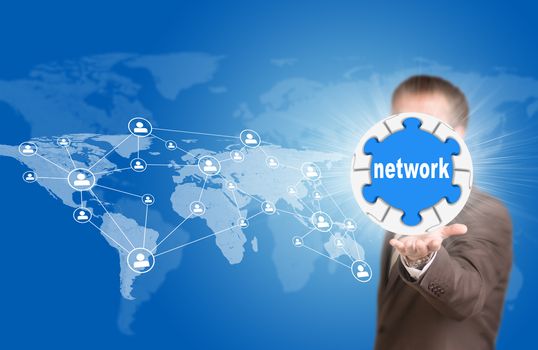Business man hold puzzle sphere with network label. World map and people icons as backdrop