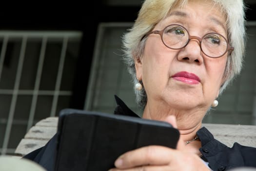 Senior women relaxing at home reading E-book on her tablet.