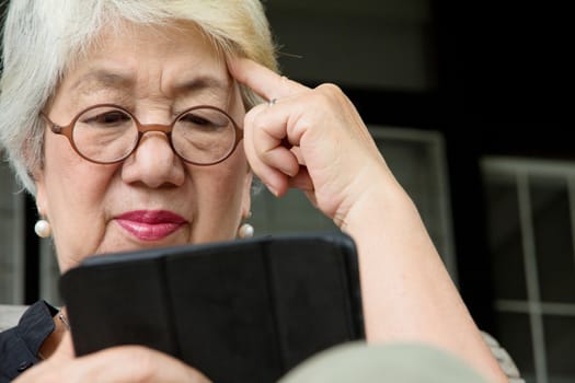 Senior women relaxing at home reading E-book on her tablet.