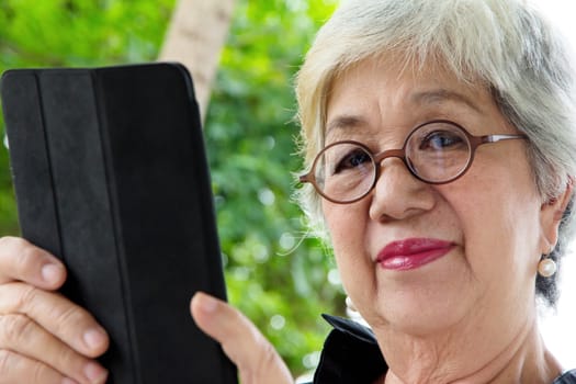 Senior women relaxing at home reading E-book on her tablet.