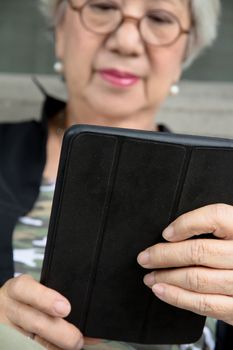 Senior women relaxing at home reading E-book on her tablet.