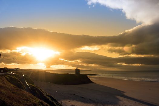 Beautiful yellow sun over the Ballybunion beach and castle in Ireland on a summers day