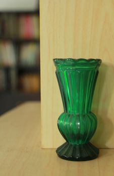 This is a green glass vase on the table.Old but still beautiful.