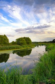 Summer landscape with the sky and clouds reflecting in the surface of the  river