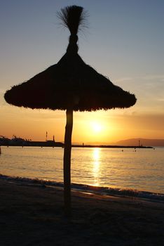 Photo is showing sunset above the beach and sea of Mallorca, Spain.