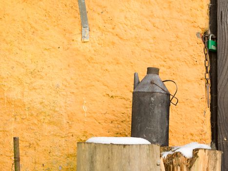 Photo presents rural country house wall with old water can.