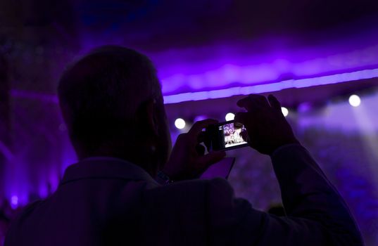 Man taking pictures with smartphone during a concert