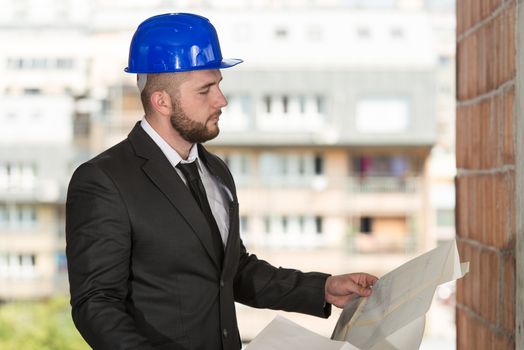 Portrait Of Construction Master With Blue Helmet And Blueprint In Hands