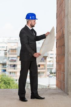 Portrait Of Construction Master With Blue Helmet And Blueprint In Hands