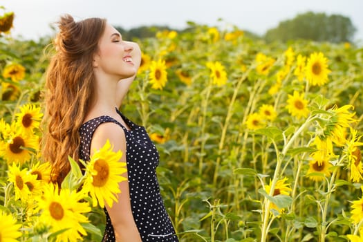 Cute girl in the field full of sunflowers