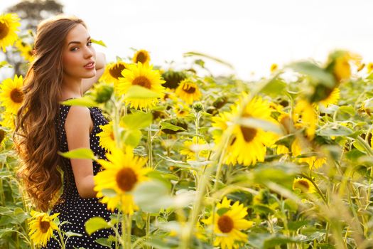 Cute girl in the field full of sunflowers