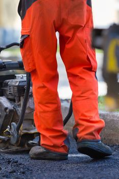 Construction workers during asphalting road works wearing coveralls. Manual labor on construction site.