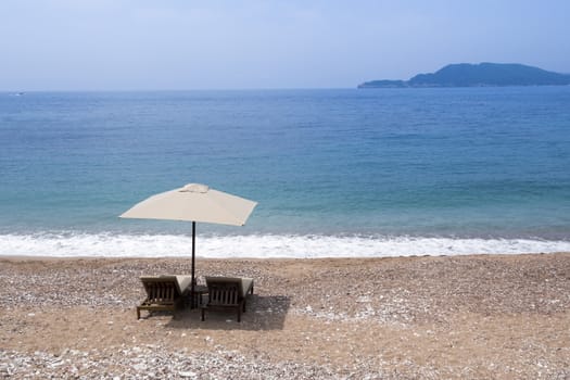 two sunbeds under sunshade on the empty sand beach