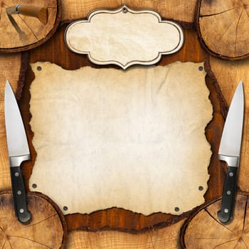 Wooden background with sections of tree trunk, two with kitchen knives, empty parchment and label. Background for a recipes or a rustic menu