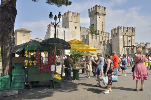 Tourists visiting Sirmione on lake Garda, Italy. with views to the Scaliger castle, built in the 13th century.  This is a rare example of medieval port fortification, which was used by the Scaliger fleet.