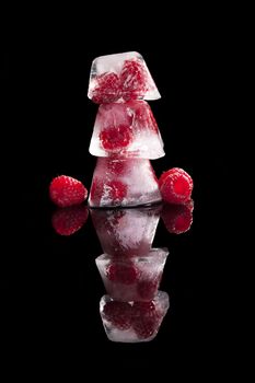 Raspberries frozen in ice cubes isolated on black background. Healthy fresh summer fruit eating. 