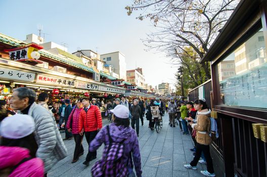 Tokyo, Japan - November 21, 2013: Tourists visit Nakamise shopping street in Asakusa, Tokyo on 21 November 2013. The busy arcade connects Senso-ji Temple to it's outer gate Kaminarimon, which can just be seen in the distance. 