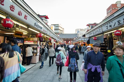 Tokyo, Japan - November 21, 2013: Tourists visit Nakamise shopping street in Asakusa, Tokyo on 21 November 2013. The busy arcade connects Senso-ji Temple to it's outer gate Kaminarimon, which can just be seen in the distance.