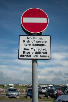 a no entry sign, with English and Welsh text warning vehicles, against a blue summer sky