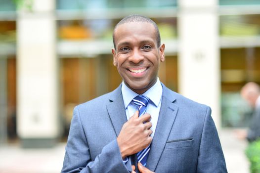 Handsome businessman fixing his tie outdoors