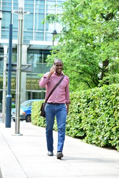 Smiling man talking on his cellphone while walking outdoors