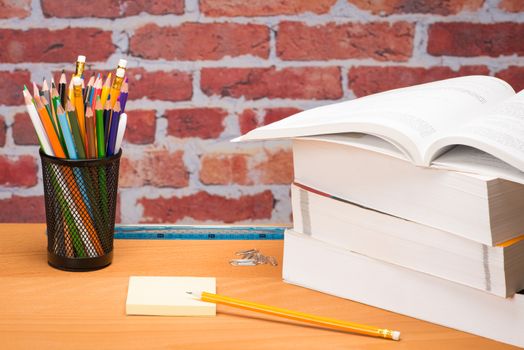 School supplies with adhesive note in front of brick wall 