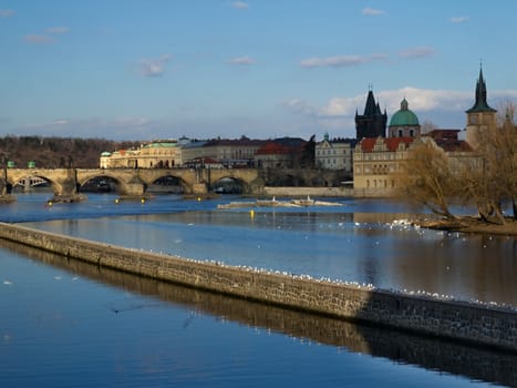 Photo shows various historical houses, Vltava river, bridges and other architectural details.