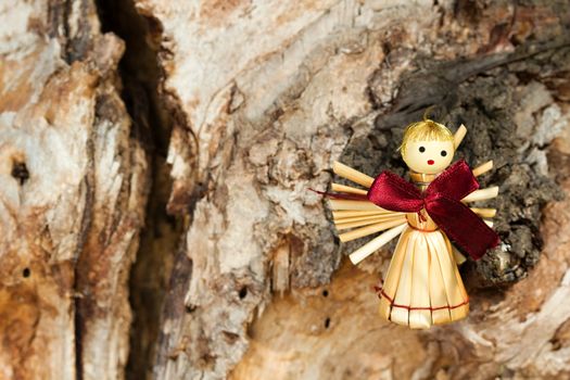 Photo shows a straw angel figurine in the wood.