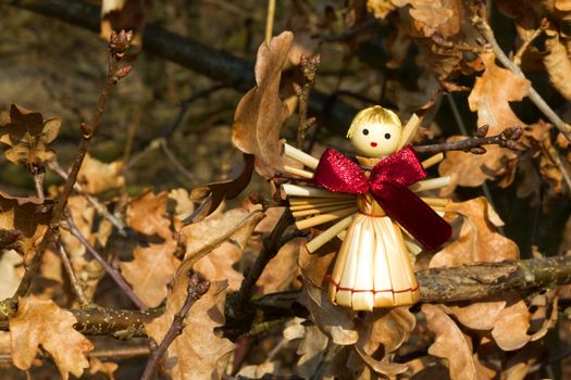 Photo shows a straw angel figurine in the wood.