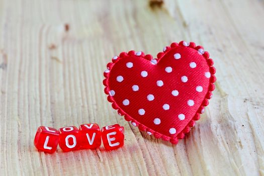 Photo shows details of love sign with heart on the wooden background.